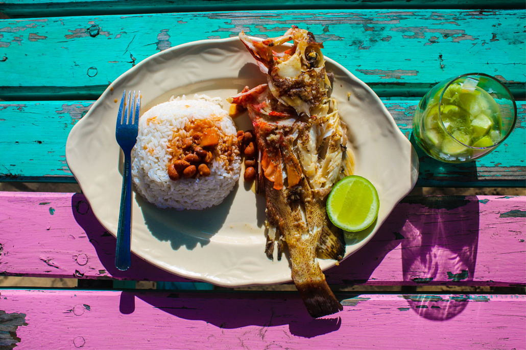 ﻿Rice, fish and a drink sitting on blue and purple wooden table